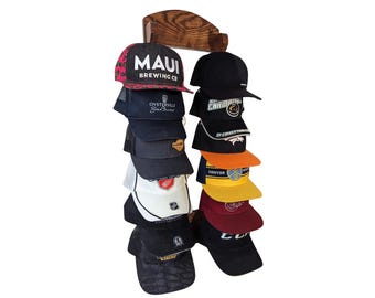 May include: A wooden hat rack with 10 baseball caps hanging on it. The caps are a variety of colors and designs, including a black cap with a white logo, a red cap with a white logo, and a blue cap with a white logo.