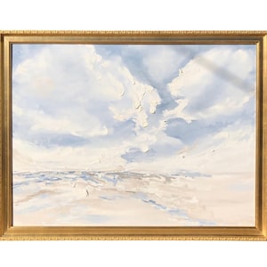 May include: An oil painting of a cloudy sky and a body of water, framed in a gold ornate frame. The painting features a palette of soft blues, whites, and beige, with textured brushstrokes creating depth and dimension.