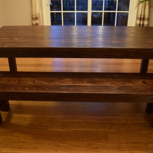 Puede incluir: Una mesa de madera marr&oacute;n oscuro con un banco a juego. La mesa y el banco tienen un estilo r&uacute;stico y de granja.
