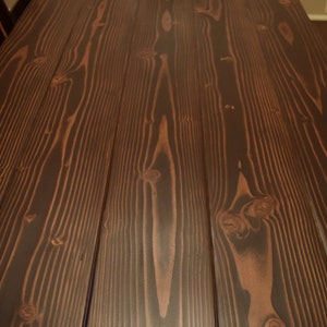 Puede incluir: Primer plano de una mesa de madera de color marr&oacute;n oscuro con un patr&oacute;n de veta de madera natural. La madera tiene un acabado liso y pulido.