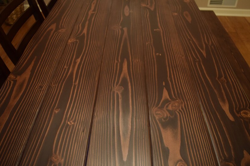 Puede incluir: Primer plano de una mesa de madera de color marr&oacute;n oscuro con un patr&oacute;n de veta de madera natural. La madera tiene un acabado liso y pulido.