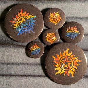 May include: Set of six round black and white buttons with a rainbow colored pentagram inside a circle of flames. The buttons are different sizes.