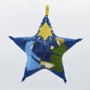 May include: A blue, green, and gold beaded star ornament depicting the nativity scene. The star is a traditional Christmas decoration.