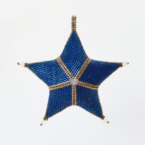 May include: A beaded star ornament in shades of blue and gold. The star is five-pointed, with a central clear gem and smaller gems at each point. Gold-colored beads outline the star's points and center. A loop at the top allows for hanging.