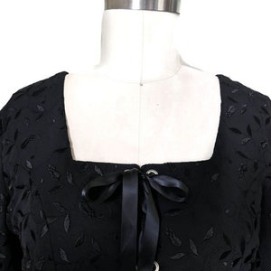 Pode incluir: Top preto de manga curta com decote quadrado e detalhe de renda na frente. O top &eacute; feito de um tecido macio e texturizado com um padr&atilde;o floral.