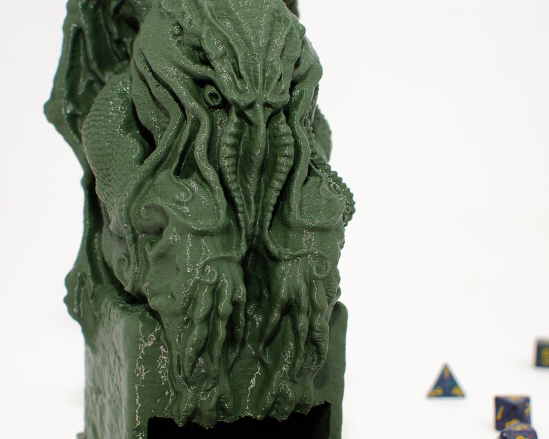 May include: Green 3D printed statue of a Cthulhu-like creature with tentacles. The statue is sitting on a base with a slot in the front.