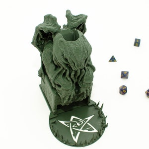 May include: Green 3D printed dice tower shaped like a Cthulhu monster with a five-pointed star base. The tower is designed to hold dice for tabletop games.
