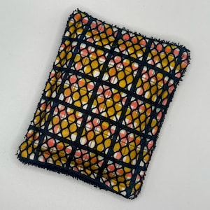 May include: A black and yellow patterned kitchen sponge with a black mesh overlay. The sponge has a frayed edge.