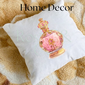 May include: White throw pillow with a pink and gold decorative bottle design. The bottle has a gold crown and intricate details.