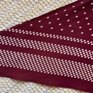 Puede incluir: Tela granate con un dise&ntilde;o de lunares y rayas blancas. La tela tiene una orientaci&oacute;n diagonal, con un patr&oacute;n que consiste en puntos blancos espaciados uniformemente y rayas horizontales de puntos blancos.