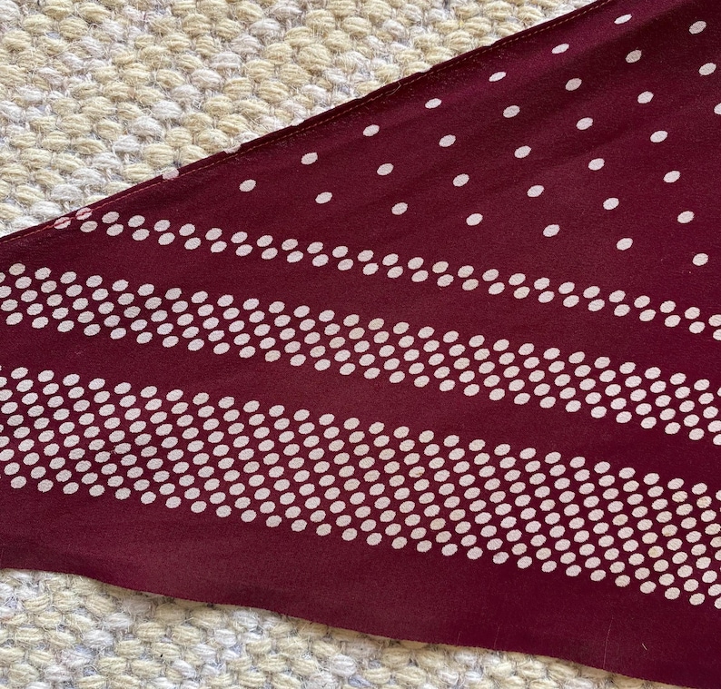 Puede incluir: Tela granate con un dise&ntilde;o de lunares y rayas blancas. La tela tiene una orientaci&oacute;n diagonal, con un patr&oacute;n que consiste en puntos blancos espaciados uniformemente y rayas horizontales de puntos blancos.