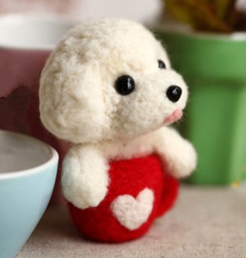 May include: White felt poodle dog figurine sitting in a red felt mug with a white heart on the front.
