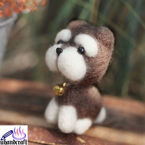 May include: A small, brown and white felt dog toy with a bell around its neck. The dog is sitting on a wooden surface.