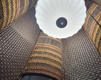 May include: A woven lampshade with a white, scalloped lampshade inside. The woven lampshade is made of brown and tan materials and has a geometric pattern.