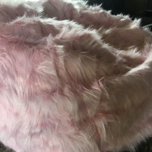 May include: A pink fluffy pet bed with a soft, plush texture.