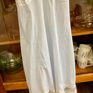 May include: A light blue slip dress with white lace trim. The dress has a fitted bodice and a flowing skirt.