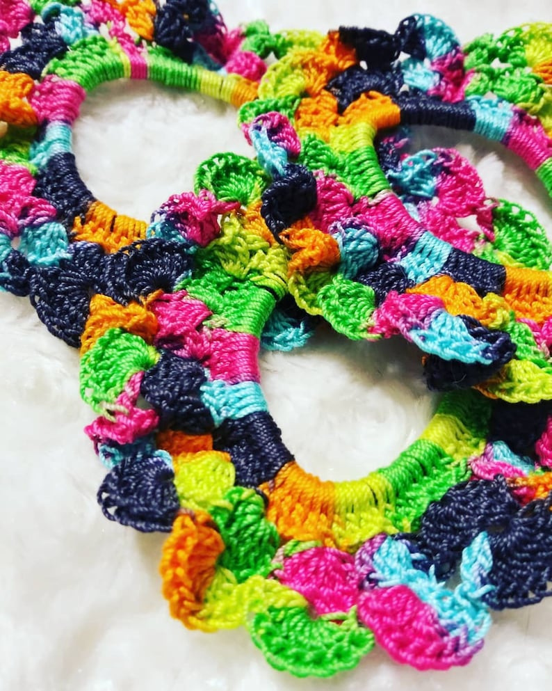 Peut inclure: Trois &eacute;lastiques &agrave; cheveux en crochet color&eacute;s dans des tons de vert, bleu, rose, orange et noir. Les &eacute;lastiques &agrave; cheveux sont faits avec un fil &eacute;pais et ont un bord festonn&eacute;.