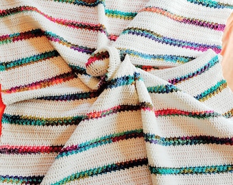 May include: A white crocheted blanket with colorful stripes in shades of pink, orange, green, blue, and purple.