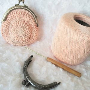 Peut inclure: Une bourse &agrave; monnaie en crochet rose avec une fermeture &agrave; fermoir en m&eacute;tal, une pelote de fil rose, un crochet et un cadre de sac &agrave; main en m&eacute;tal.