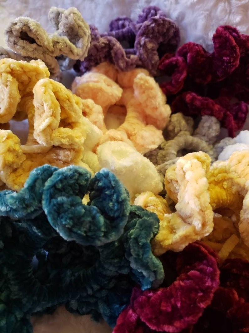 Puede incluir: Una colecci&oacute;n de scrunchies peludos de colores en varios tonos de rosa, amarillo, azul, morado y rojo. Los scrunchies est&aacute;n hechos de un material suave y aterciopelado y son perfectos para agregar un toque de color y estilo a cualquier peinado.