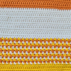 May include: A crocheted blanket with stripes of orange, white, orange and yellow yarn.