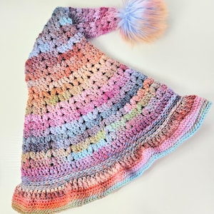 以下が含まれることがあります： カラフルな毛糸で編まれた帽子で、ふわふわのポンポンがついたものです。帽子はピンク、ブルー、グリーンの様々な色合いで作られています。