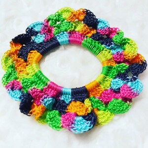Peut inclure: Un chouchou pour cheveux en crochet color&eacute; avec une forme circulaire et une vari&eacute;t&eacute; de couleurs, notamment le vert, le bleu, le rose, l'orange et le noir.