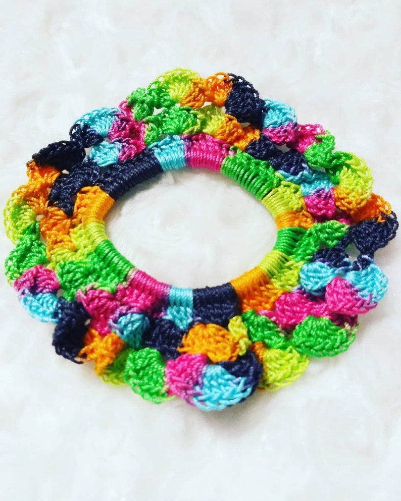 Peut inclure: Un chouchou pour cheveux en crochet color&eacute; avec une forme circulaire et une vari&eacute;t&eacute; de couleurs, notamment le vert, le bleu, le rose, l'orange et le noir.