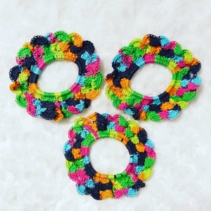 Peut inclure: Trois &eacute;lastiques &agrave; cheveux en crochet color&eacute;s dans des tons de vert, bleu, rose, orange et noir. Les &eacute;lastiques &agrave; cheveux sont dispos&eacute;s en forme de triangle sur une surface blanche et duveteuse.