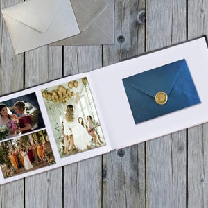 Könnte beinhalten: Ein offenes Fotoalbum mit Hochzeitsfotos, einem blauen Umschlag mit goldenem Wachssiegel und zwei Umschlägen auf einer Holzoberfläche. Auf der rechten Seite liegt ein schwarzer Stift. Das Album zeigt mehrere Fotos einer Hochzeitszeremonie.