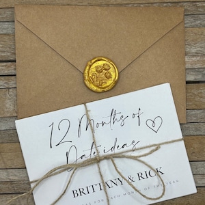 May include: A brown envelope sealed with a gold wax seal, and a white card tied with twine. The card reads "12 Months of Date Ideas" with the names "Brittany & Rick" and "Date Ideas for Each Month of the Year."