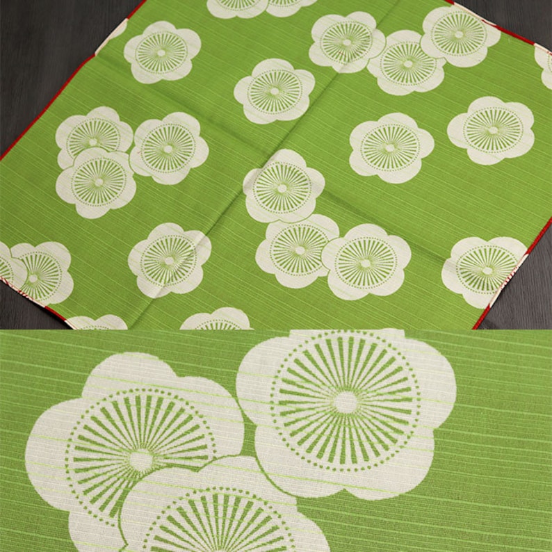 May include: Green fabric with a white floral pattern. The flowers have a circular design with a white center and green lines radiating outward.