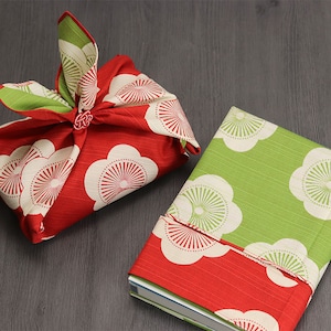 May include: Two fabric gift wrapping techniques using a red and white floral patterned fabric and a green and white floral patterned fabric.