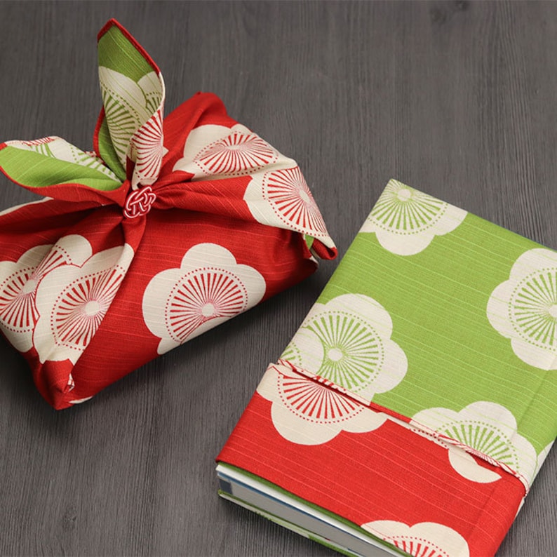 May include: Two fabric gift wrapping techniques using a red and white floral patterned fabric and a green and white floral patterned fabric.