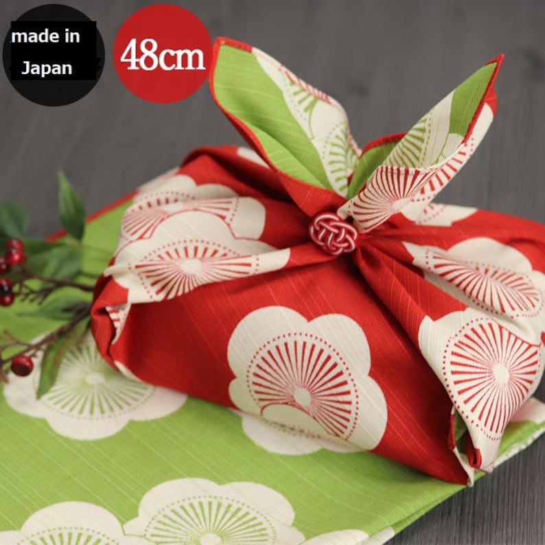 May include: Red and green fabric gift wrap with white floral pattern. The fabric is tied with a knot and the ends are folded over. The fabric is labeled "made in Japan" and "48cm".