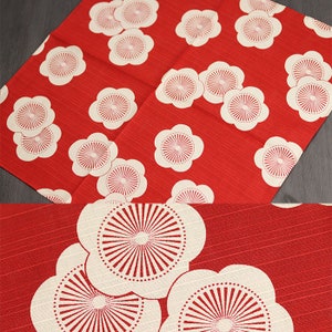 May include: Red fabric with a white floral pattern. The flowers have a white center with a red circle in the middle. The fabric has a subtle texture.