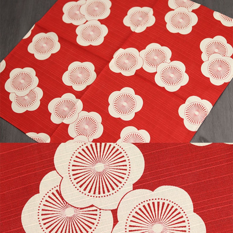 May include: Red fabric with a white floral pattern. The flowers have a white center with a red circle in the middle. The fabric has a subtle texture.