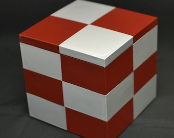 May include: A red and white checkered cube box. The box is made of wood and has a smooth, polished finish.