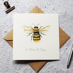May include: A white card with a watercolour illustration of a bee with yellow and black stripes. The text "A Note To Say..." is printed below the bee.