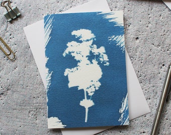 May include: A blue card with a white silhouette of a flower or plant. The card has a textured background and a white border.