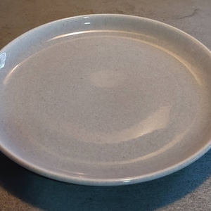 May include: A light gray ceramic plate with a slightly textured surface.