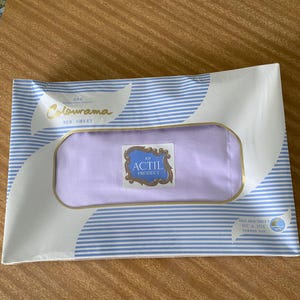 May include: A packaged lavender-colored bed sheet, labeled "Colourama Bed Sheet" with a blue and white striped design. The package includes the text "AN ACTIL PRODUCT" and the dimensions of the sheet are 63 x 104 inches.