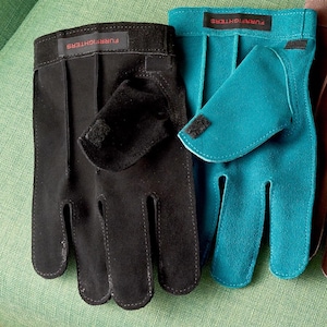 K&ouml;nnte beinhalten: Zwei Paar Wildlederhandschuhe, ein schwarzes und ein blaues Paar, mit dem Text "FURRIGHTER" auf der R&uuml;ckseite jedes Handschuhs.