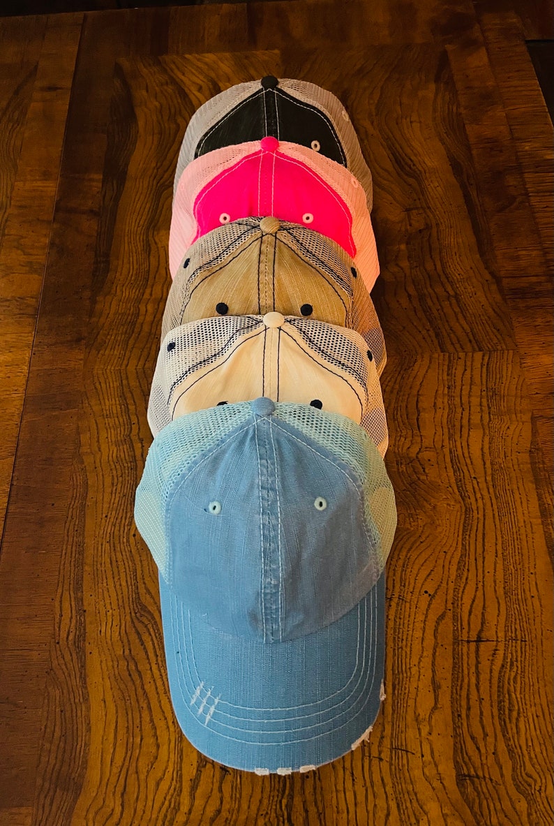 K&ouml;nnte beinhalten: Stapel von f&uuml;nf Baseballkappen in verschiedenen Farben. Die unterste Kappe ist hellblau, die n&auml;chste ist wei&szlig;, die n&auml;chste ist beige, die n&auml;chste ist rosa und die oberste Kappe ist schwarz.