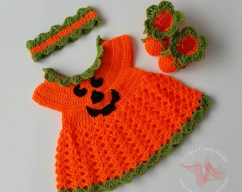 May include: Orange and green crocheted pumpkin costume for a baby. The costume includes a dress, headband, and booties. The dress has a pumpkin face on the front. The headband is a simple band with a green crocheted edge. The booties are shaped like pumpkins with green crocheted leaves.