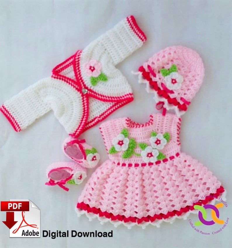 Op de afbeelding: Een gehaakte baby outfit set in roze en wit met bloemmotieven. De set bevat een jurkje, een vest, een muts en slofjes. De outfit is perfect voor een pasgeboren baby meisje.