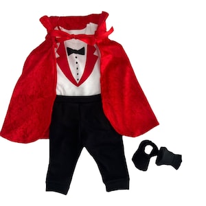 May include: A white bodysuit featuring a printed red tuxedo jacket, black bowtie, and three black buttons, paired with black pants, a red velvet cape with a ribbon tie, and two black booties. This ensemble creates a formal tuxedo appearance.