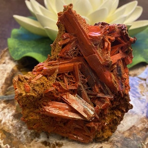 Könnte beinhalten: Ein Cluster aus orangefarbenen und braunen Kristallen mit einer rauen, strukturierten Oberfläche. Die Kristalle sind in einem zufälligen Muster angeordnet, was eine einzigartige und interessante Darstellung ergibt.