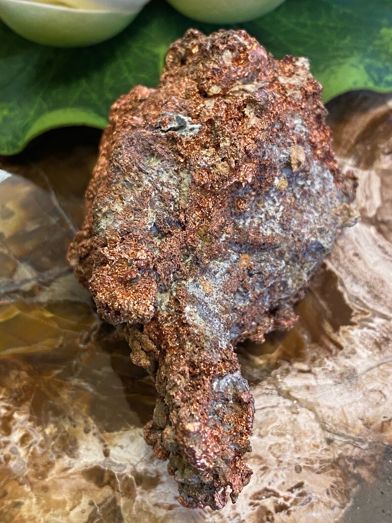 Puede incluir: Una roca grande, rugosa, de color cobre con un brillo met&aacute;lico. La roca tiene una forma &uacute;nica, irregular y una superficie texturizada.