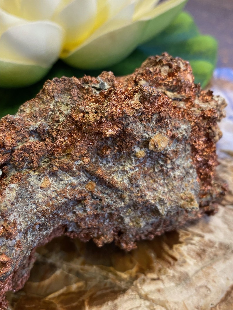 Puede incluir: Primer plano de una roca rugosa de color cobre con una superficie texturizada. La roca tiene un brillo met&aacute;lico y parece ser un mineral natural.